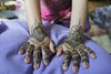 A child enjoys a henna design session with colorful patterns at a party setting.
